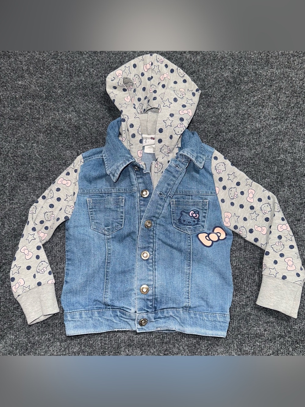 Hello Kitty denim jacket with zip up hood and pink bow graphic on the sleeve